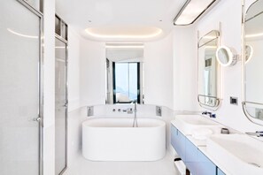 Une salle de bain moderne avec une grande baignoire, deux lavabos et un grand miroir.