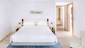 A modern hotel room with a large bed, a blue patterned rug, and a wooden chair. - The Maybourne Riviera (Roquebrune-Cap-Martin)