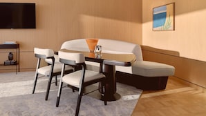 A modern room with a sofa, two chairs, a table, a flat-screen TV, and a painting on the wall. - The Maybourne Riviera (Roquebrune-Cap-Martin)