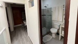 Un corridoio stretto che conduce a un bagno con il water, doccia e un piccolo tavolo con sedie.