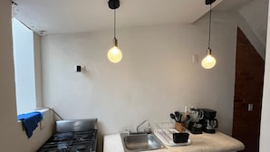 Una cucina compatta con piano cottura a gas, lavello e lampade a sospensione.