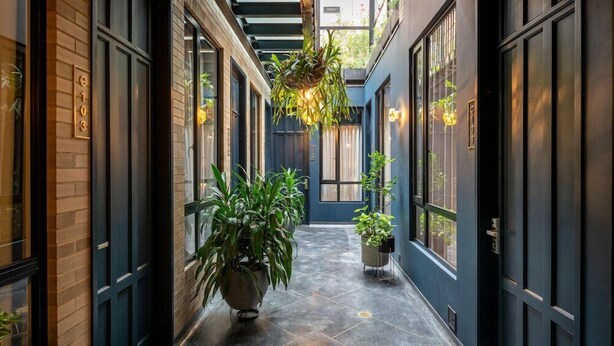 A narrow hallway with potted plants, a hanging light fixture, and a door labeled 'Patio'.