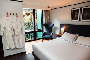 Ein Hotelzimmer mit Bett, Sessel, Schreibtisch und Lampe sowie einer Wand mit gerahmten Bildern.