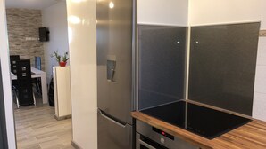 A modern kitchen with a stainless steel refrigerator, a built-in oven, and a wooden countertop. - Beautiful modern apartment near the sea (Frontignan)