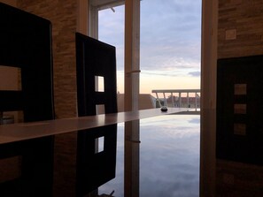 A room with a large window, a white railing, and a view of buildings and clouds. - Beautiful modern apartment near the sea (Frontignan)