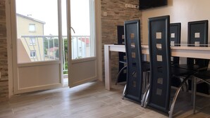 A room with a sliding glass door leading to a balcony, a flat-screen TV mounted on the wall, and a dining table with chairs. - Beautiful modern apartment near the sea (Frontignan)