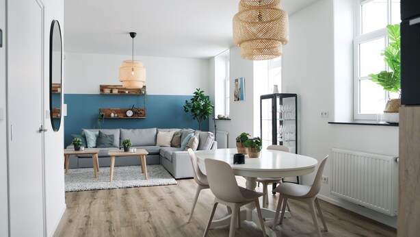 A modern living room with a sofa, a dining table with chairs, a hanging light fixture, and a window with plants. - Sfeervol Vakantiehuis in Centrum Yerseke (Yerseke)