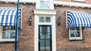 A brick building with a black door and windows with blue-striped awnings. - Sfeervol Vakantiehuis in Centrum Yerseke (Yerseke)