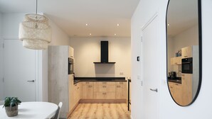 A modern kitchen with wooden cabinets, a black range hood, and a round mirror. - Sfeervol Vakantiehuis in Centrum Yerseke (Yerseke)