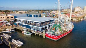 A large, multi-level docked ship with a blue and white building adjacent to it, featuring outdoor seating and a view of the water. - Beach Getaway: Stunning, Family-Friendly w/ Pool. Walk to Shopping + Dining (Atlantic Beach)