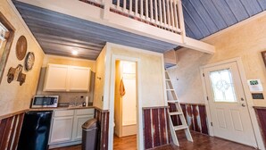 Ein geräumiges Loft mit Küche, einer Treppe zu einer oberen Ebene und einer Tür mit Fenster.