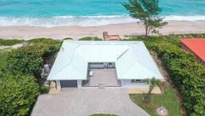 A beachfront property with a large house, a driveway, and a lawn.