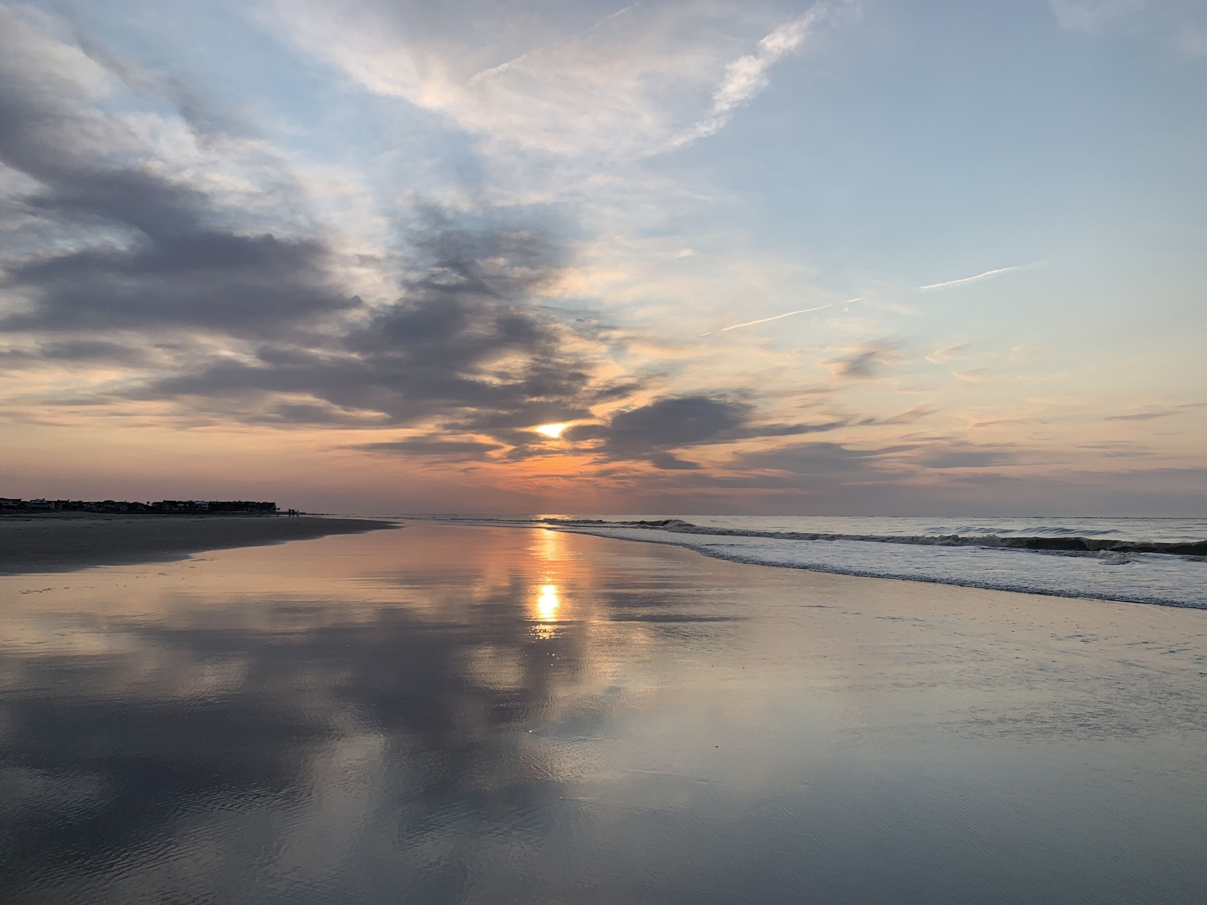 A beach with a calm sea and a sunset.