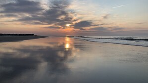 Une plage avec une mer calme et un coucher de soleil.