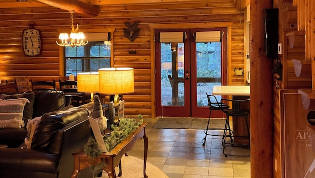 A log cabin interior with a wooden ceiling, a dining area, a fireplace, and a large window. - Luxury Log Cabin Living! AC, Kid & Pet Friendly, Fishing, Hiking, Golf (Pinetop)