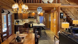A cabin interior with a dining area, kitchen, and a staircase leading to a loft. - Luxury Log Cabin Living! AC, Kid & Pet Friendly, Fishing, Hiking, Golf (Pinetop)