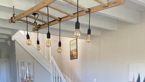 Een moderne woonkamer met een houten salontafel, blauwe en grijze banken, een trap en hangende lampen.