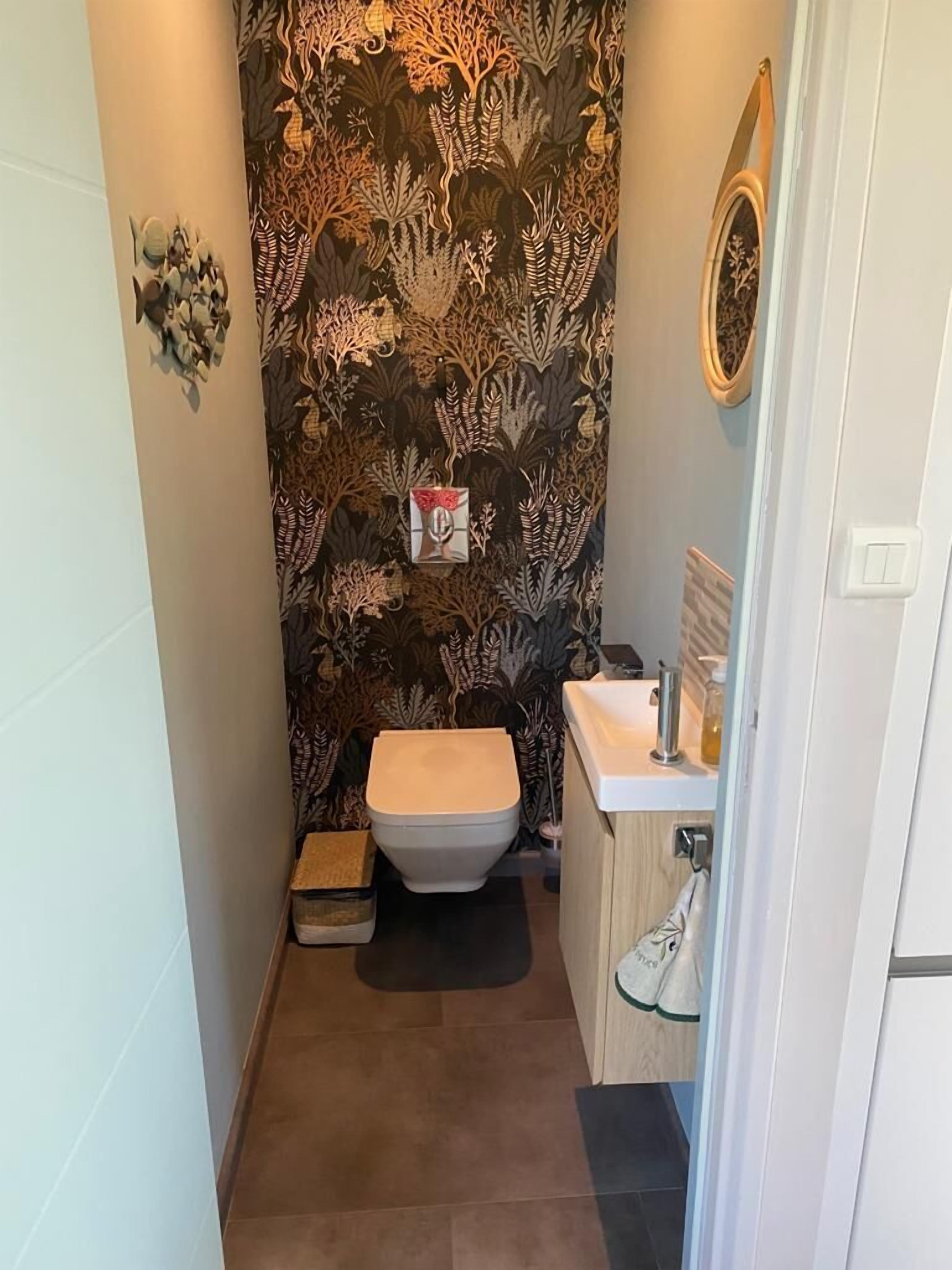 A small bathroom with a toilet, sink, and decorative wall.