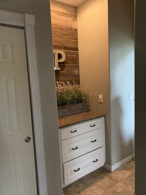 A hallway with a wooden accent wall, a white door, and a countertop with drawers.