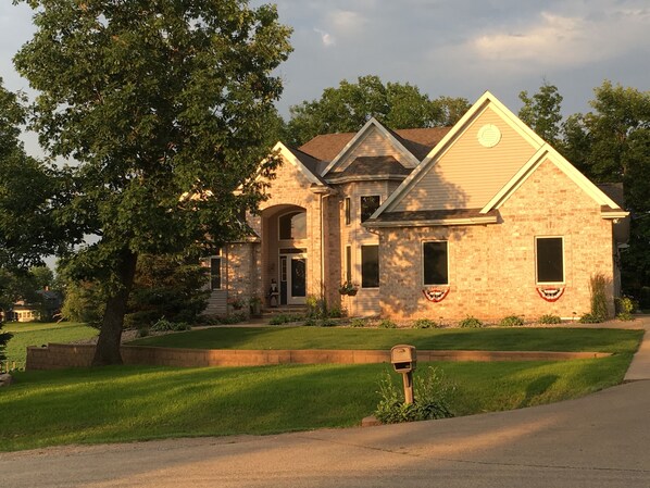 A two-story house with a stone facade, a front porch, and a flag on the front door.