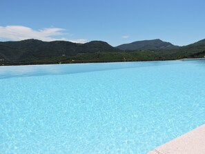 Una piscina azul cristalina con vistas a montañas verdes al fondo.
