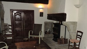 Una habitación tradicional con puerta de madera, dos sillas, chimenea y pared de piedra.