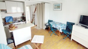 A compact kitchen with a dining area, a small TV, and a window with a view. - Maisonnette Biscarrosse Plage 300m de Locéan (Biscarrosse)