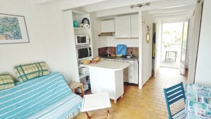 A compact living space with a kitchenette, a dining area, and a sofa. - Maisonnette Biscarrosse Plage 300m de Locéan (Biscarrosse)