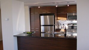 Una cocina moderna con armarios de madera oscura, electrodomésticos de acero inoxidable y encimera de granito.