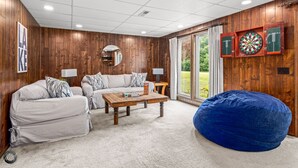 A cozy living room with a wooden wall, a sofa, a coffee table, and a bean bag. - Lakefront Home w/ Private Dock & MTB Trails Minutes from Bentonville (Bella Vista)