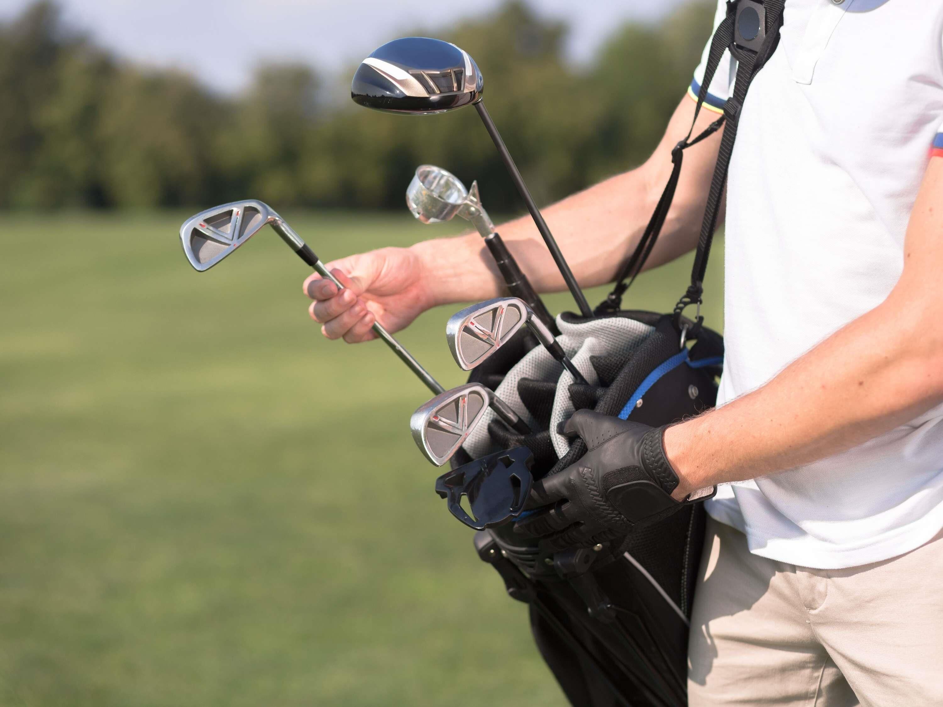 Una persona sosteniendo un bolso de golf con varios palos.