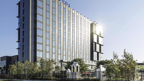 A modern hotel building with a prominent 'NOVOTEL' sign, multiple floors, and a gated entrance. - Novotel Bangkok Future Park Rangsit (Thanyaburi)