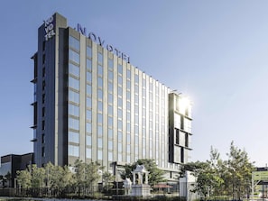 A modern hotel building with a prominent 'NOVOTEL' sign, multiple floors, and a gated entrance. - Novotel Bangkok Future Park Rangsit (Thanyaburi)