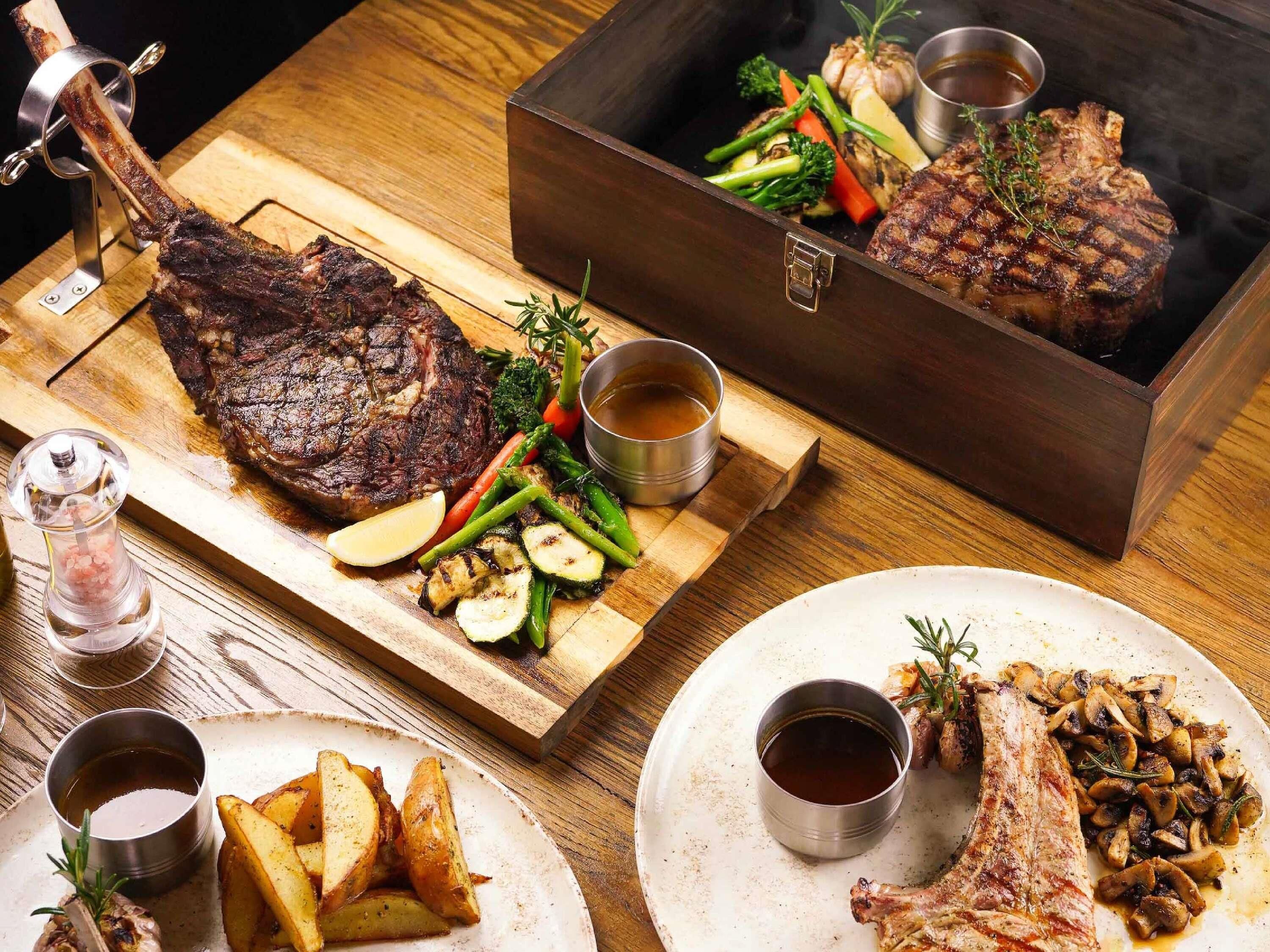 A dining table with a variety of meats, vegetables, and sauces.