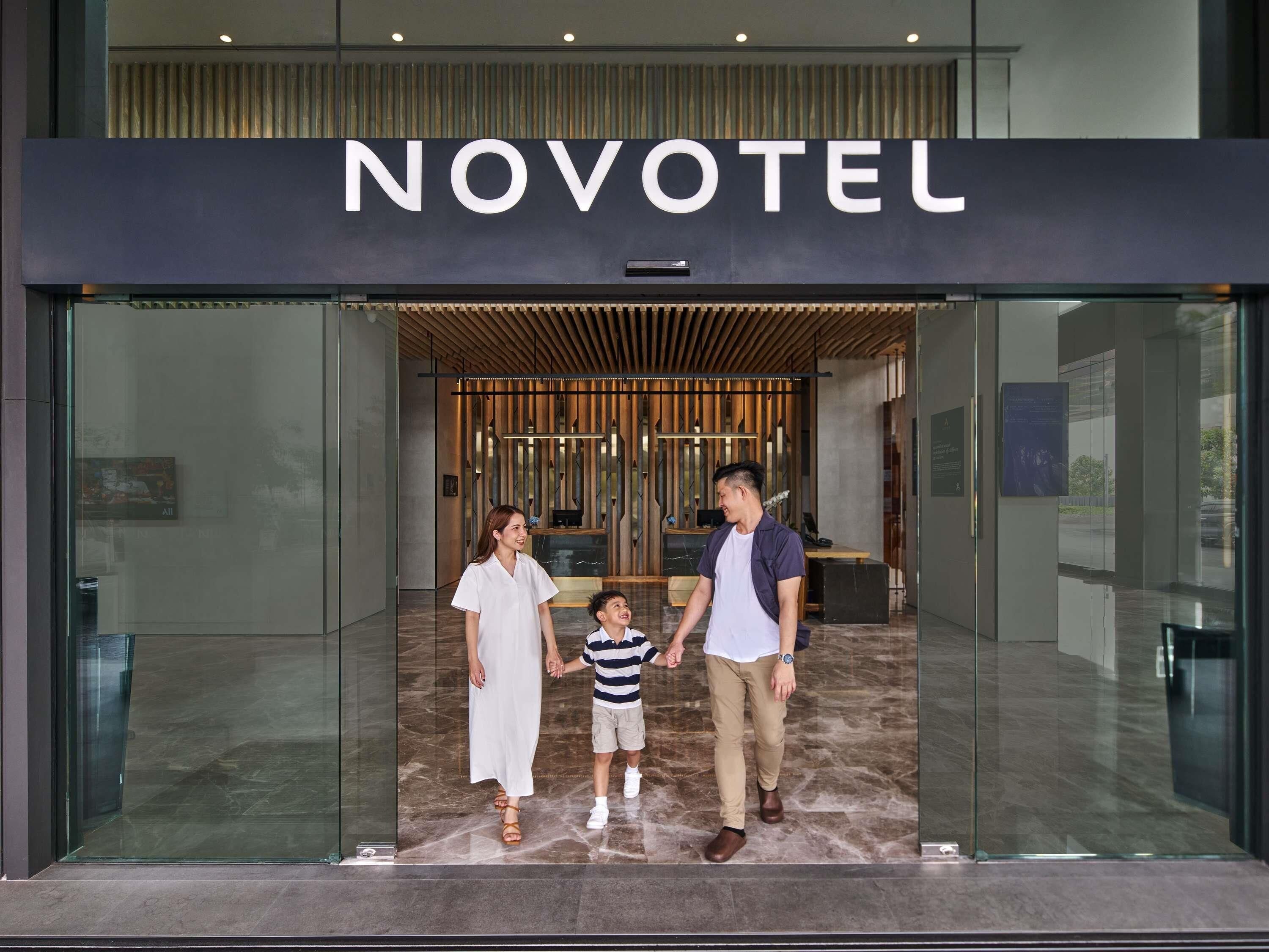 Fachada de un hotel de diseño moderno, con una recepción y una familia de pie frente a ella.
