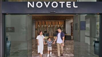 Fachada de un hotel de diseño moderno, con una recepción y una familia de pie frente a ella.