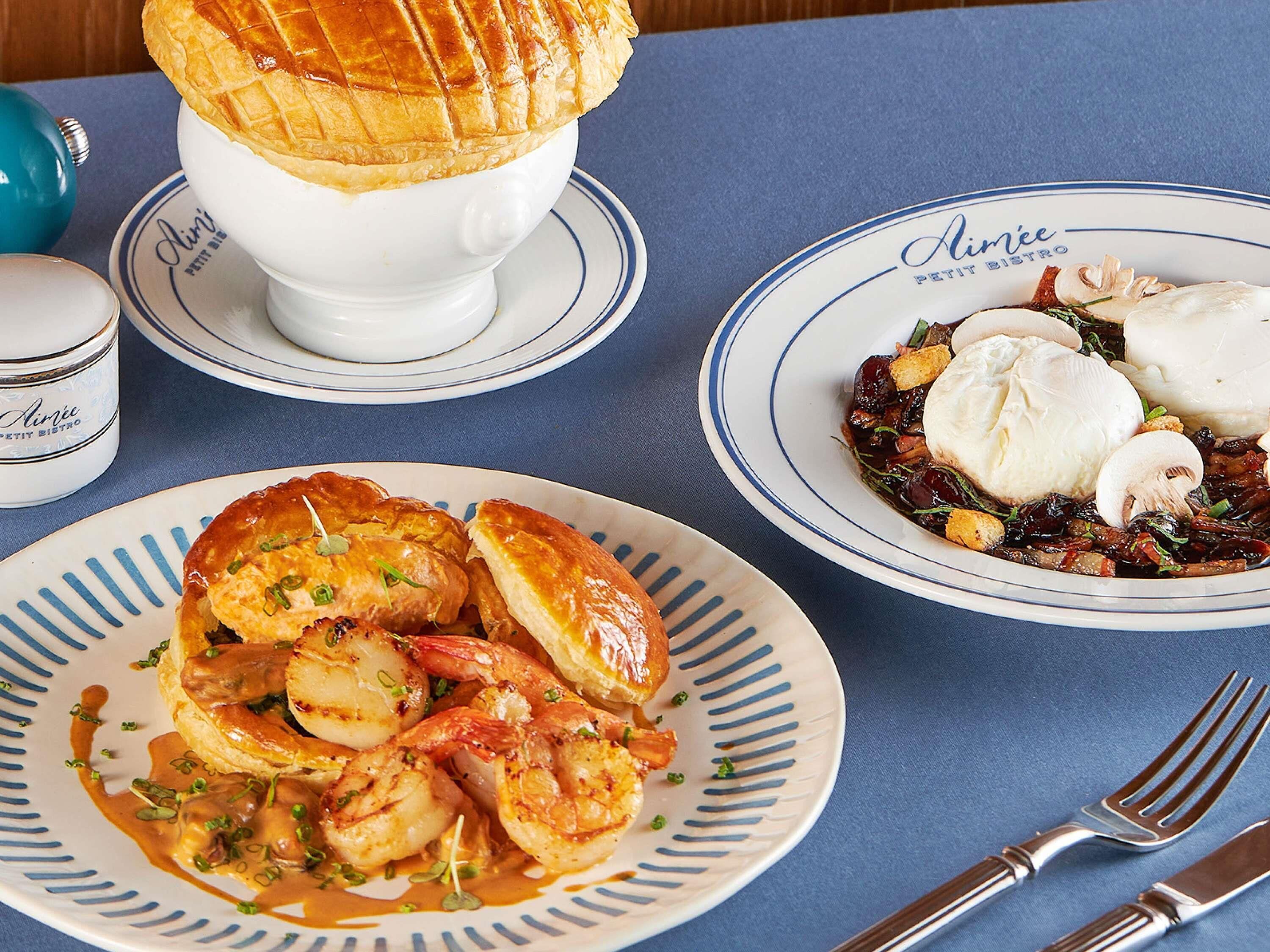 A table with three plates of food, a teapot, and a cup.