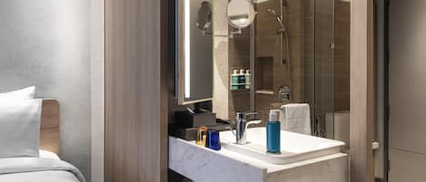 A modern bathroom with a marble sink, a glass shower enclosure, and a large mirror.