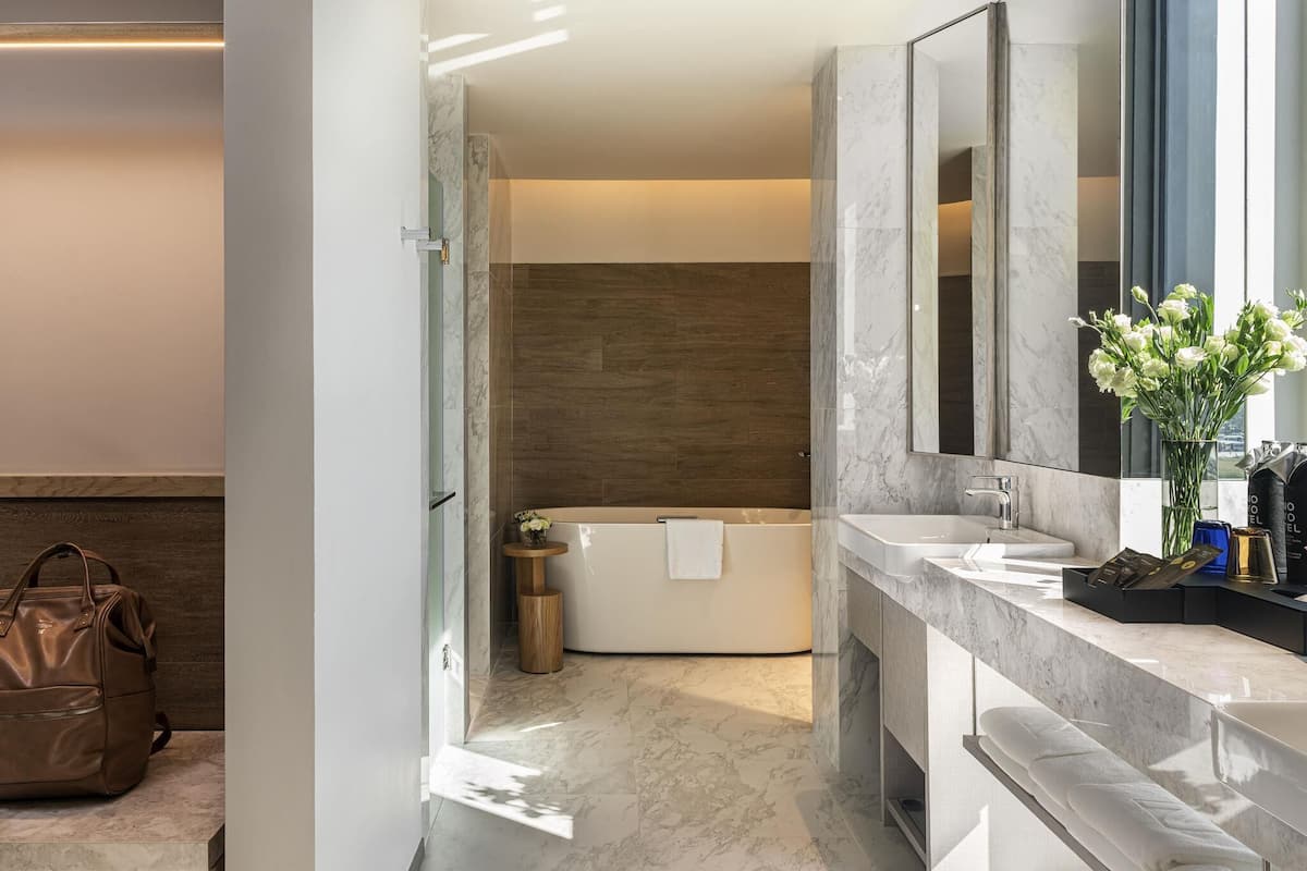 Un baño moderno con una bañera, un espejo grande y un mueble de tocador con lavabo.