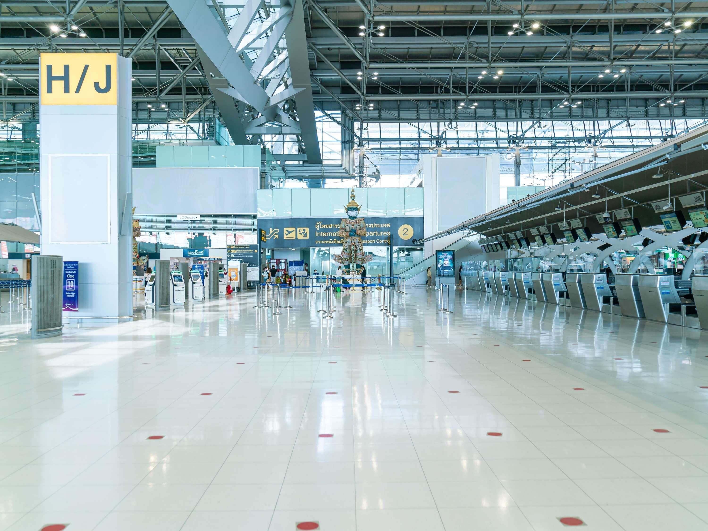 A spacious airport terminal with clear signage, including a prominent 'H/J' sign, and multiple check-in counters.