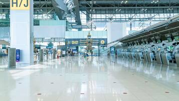 A spacious airport terminal with clear signage, including a prominent 'H/J' sign, and multiple check-in counters.