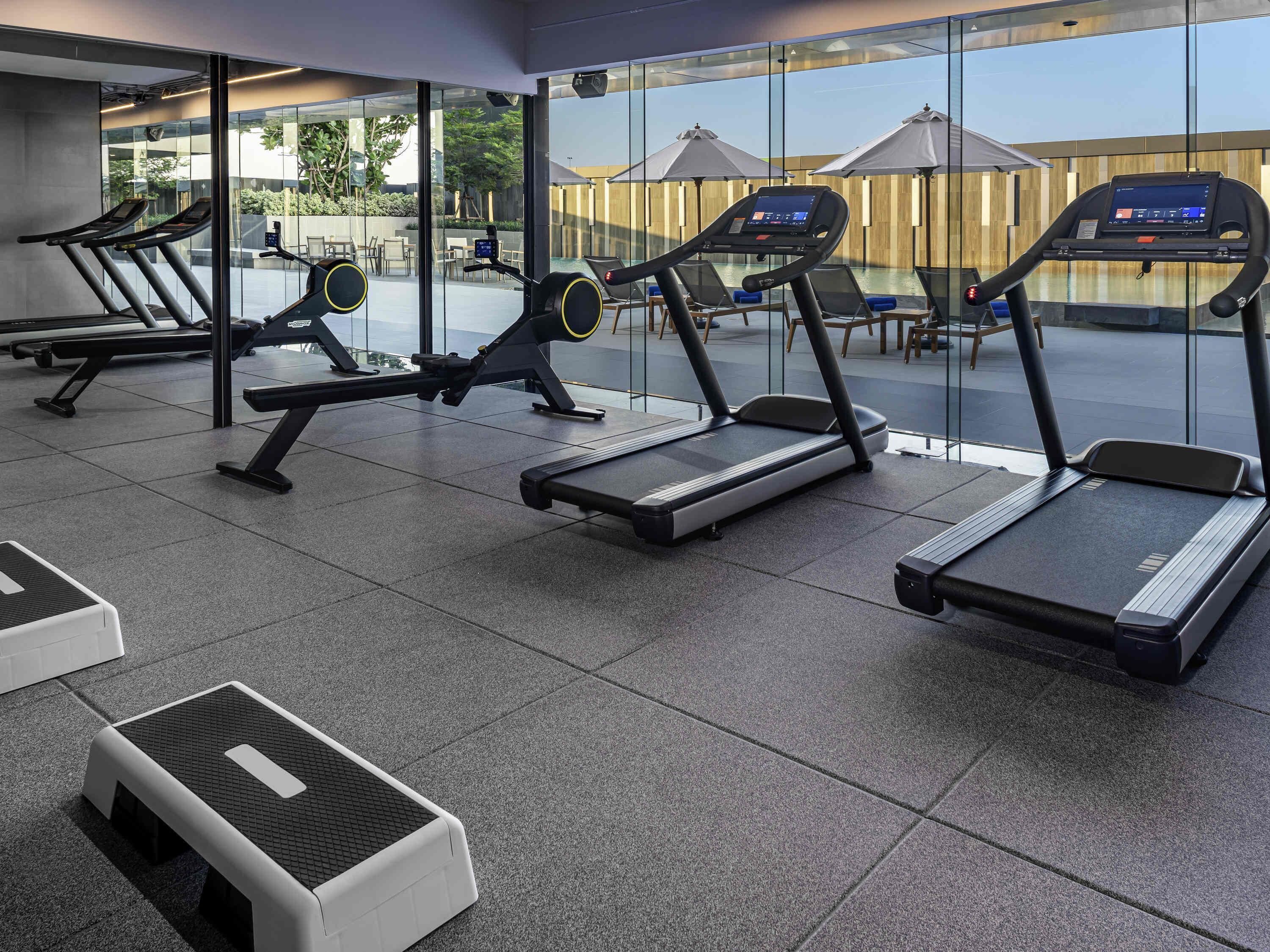Una palestra con tapis roulant, panca piana e vogatore.