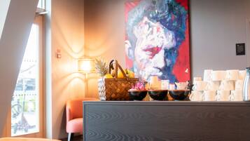 A modern interior with a wooden cabinet, a fruit basket, and a large abstract painting on the wall.
