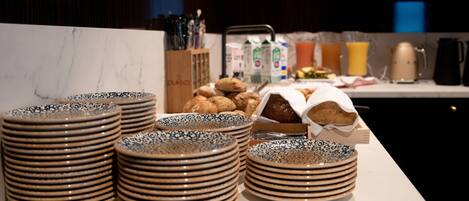 Stacks of patterned plates and a tray of pastries on a marble countertop in a kitchen setting.