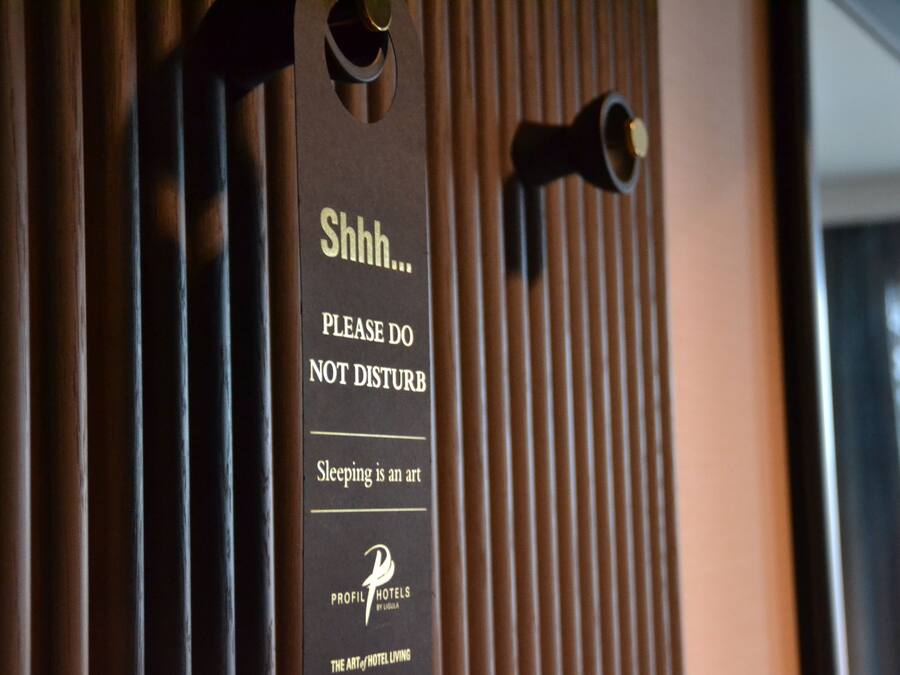 A sign on a door with the text "Shhh... PLEASE DO NOT DISTURB. Sleeping is an art. PROFILE HOTELS BY LOUISA. THE ART OF HOTEL LIVING."