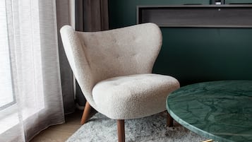 Una habitación moderna con un sillón color crema, una mesa de mármol verde y un estante de madera oscura.