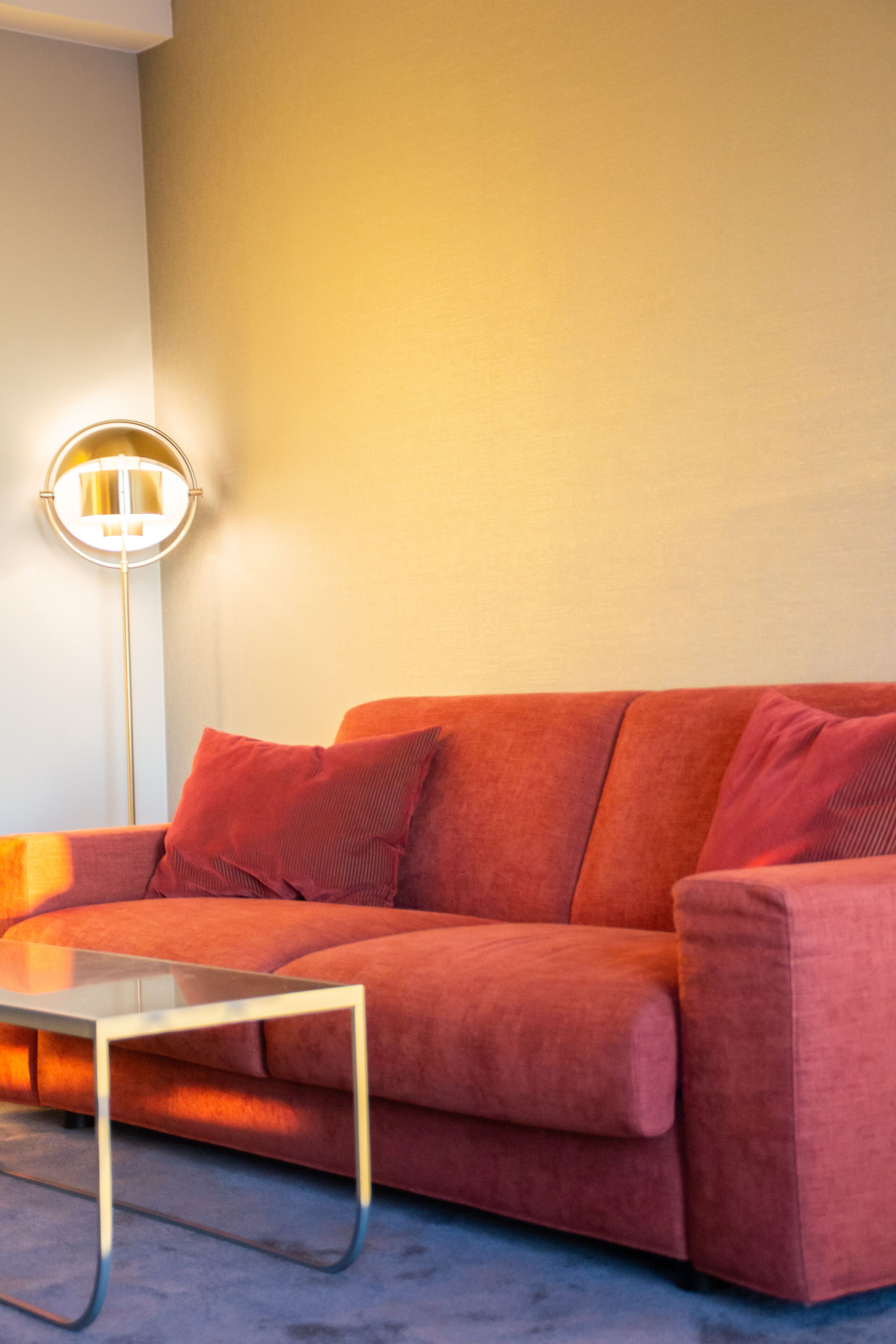 A modern living room with a red sofa, a glass coffee table, and a floor lamp.
