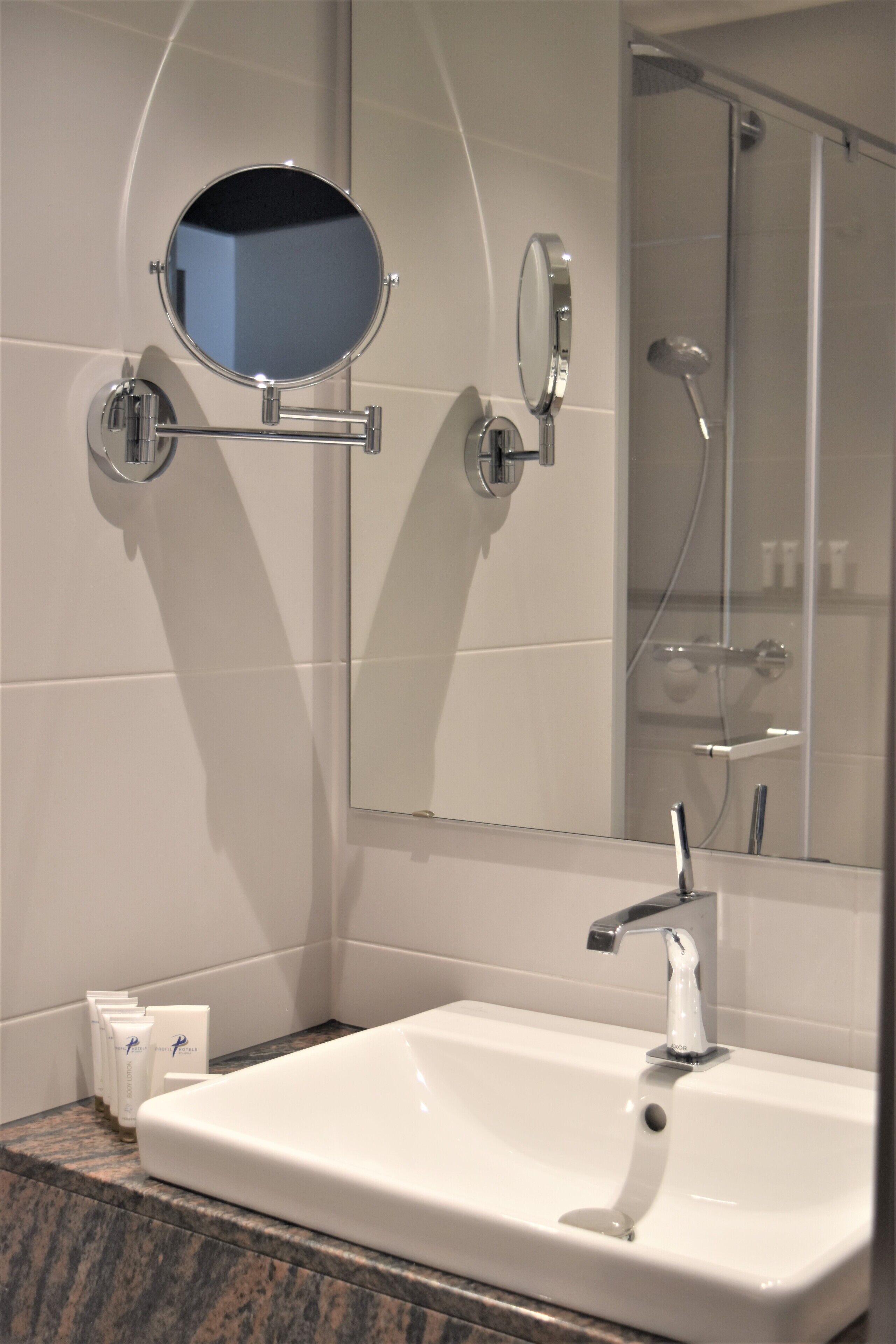 A bathroom with a white sink, a mirror, and a shower.
