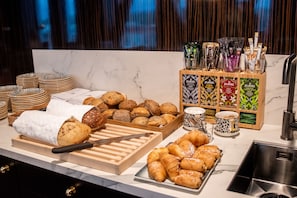 Enjoy a variety of baked goods and beverages at our buffet, featuring an assortment of breads, pastries, and croissants.