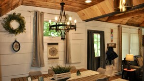 A wooden dining table with chairs, a chandelier, and a plant centerpiece. - Relax Refresh & Reconnect  Lakefront on Autumn Lake, 3min to Salmon River (Orwell)